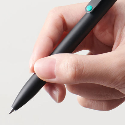 Hand holding a black pen with a green button on a light gray background
