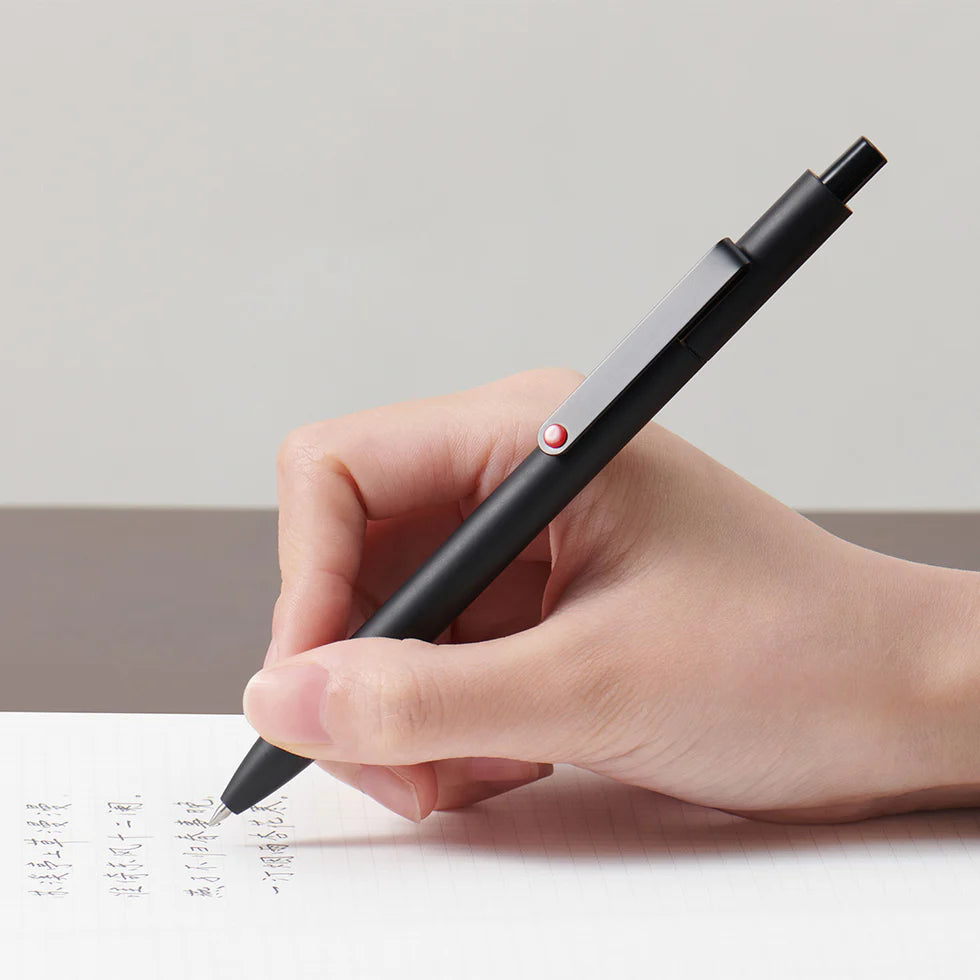 Hand holding a black pen writing on a piece of paper with a minimal background