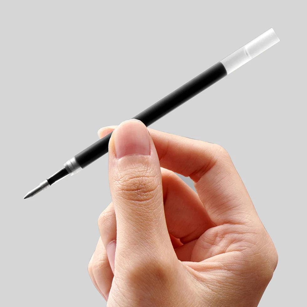 Hand holding a black and clear pen against a gray background