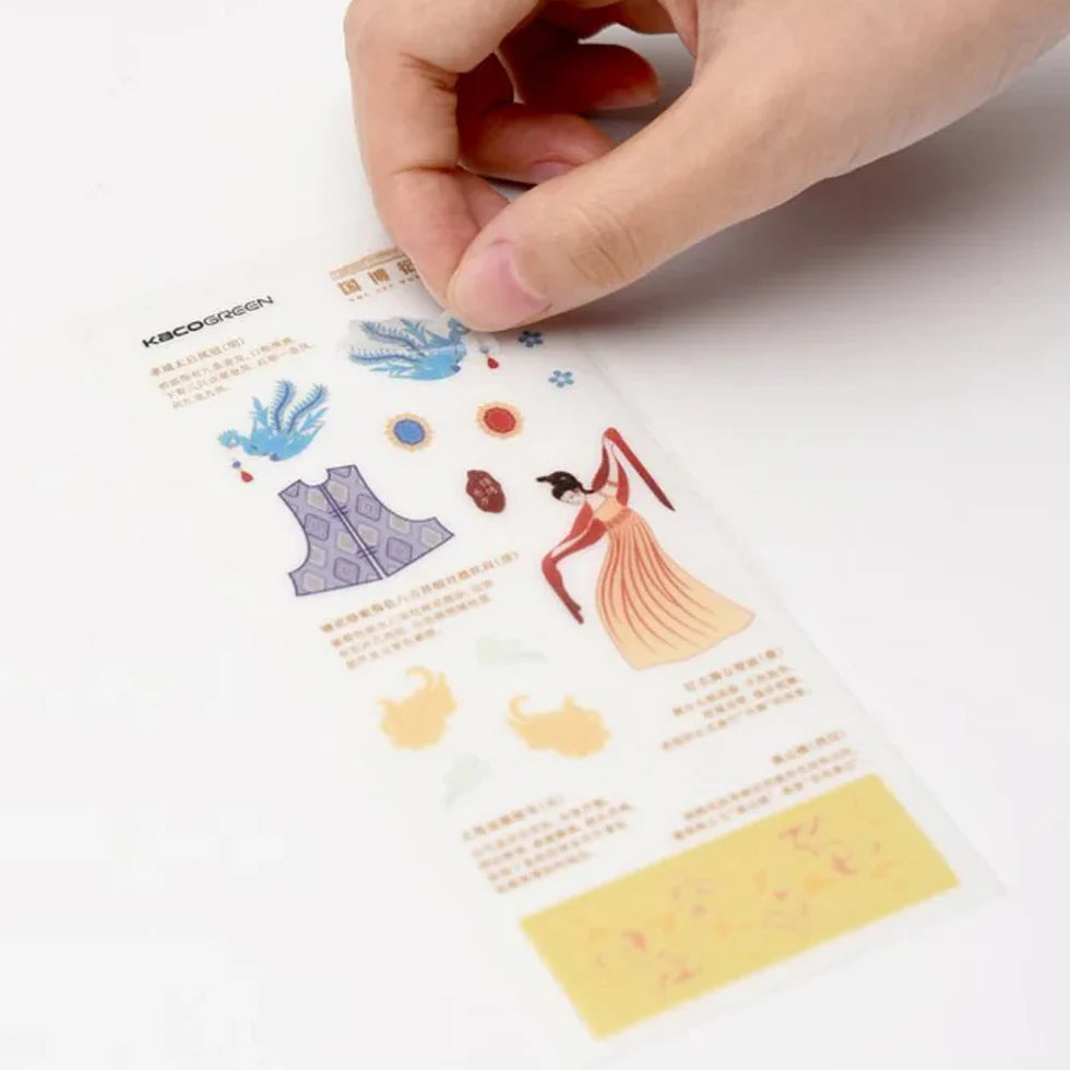 Hand holding a sheet of temporary tattoos with various designs on a white background