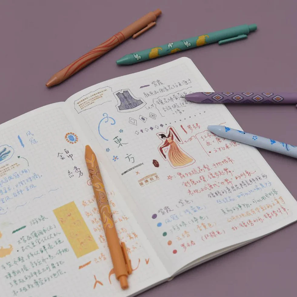 Open notebook with colorful pen designs on a purple background
