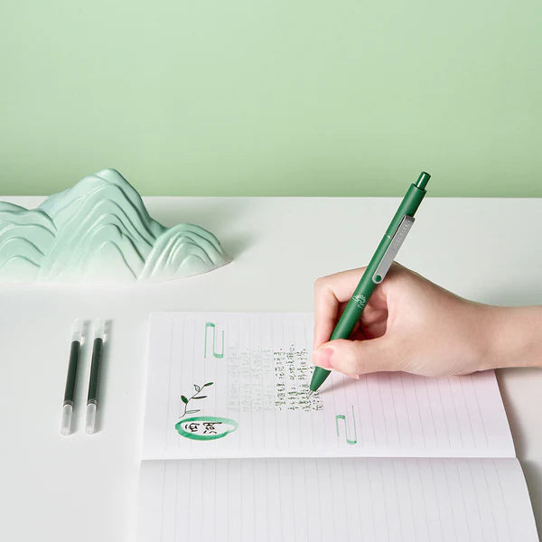Hand holding a green pen writing on a notebook with a green background