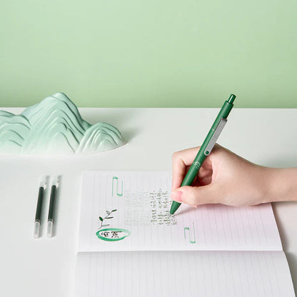 Hand holding a green pen writing on a notebook with a green background