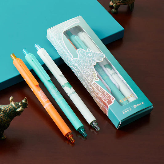 Four pens with different colored caps in front of a branded pen box on a wooden surface.