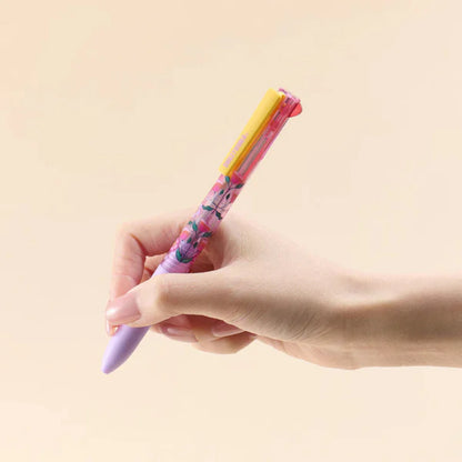 Hand holding a colorful pen against a beige background