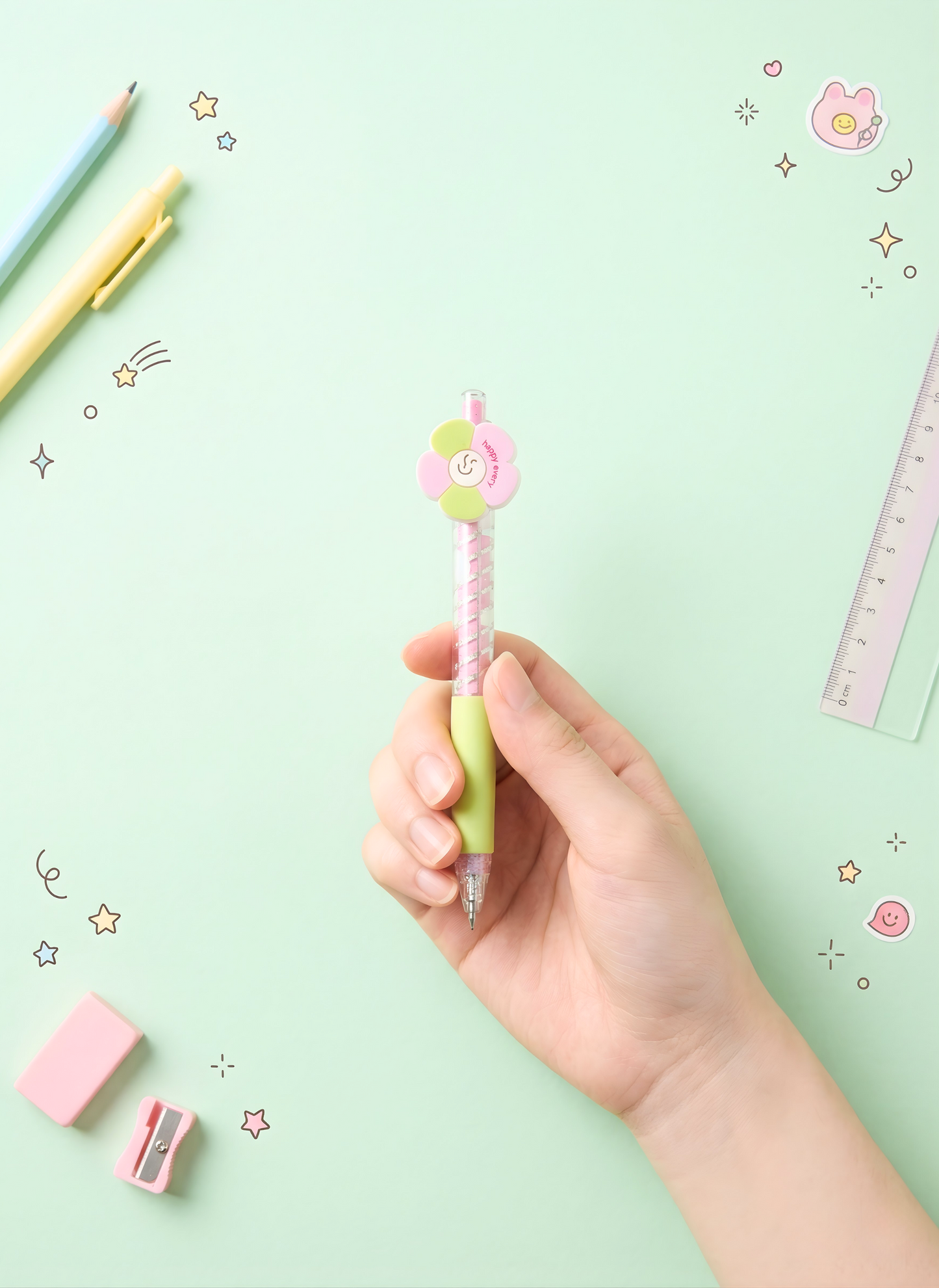 Hand holding a decorative pen with stationery items on a light green background