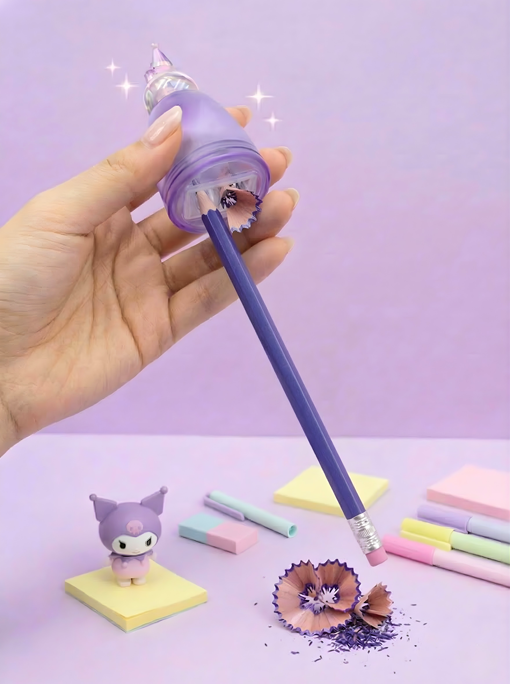 Hand holding a purple pencil with a decorative pencil sharpener against a light purple background