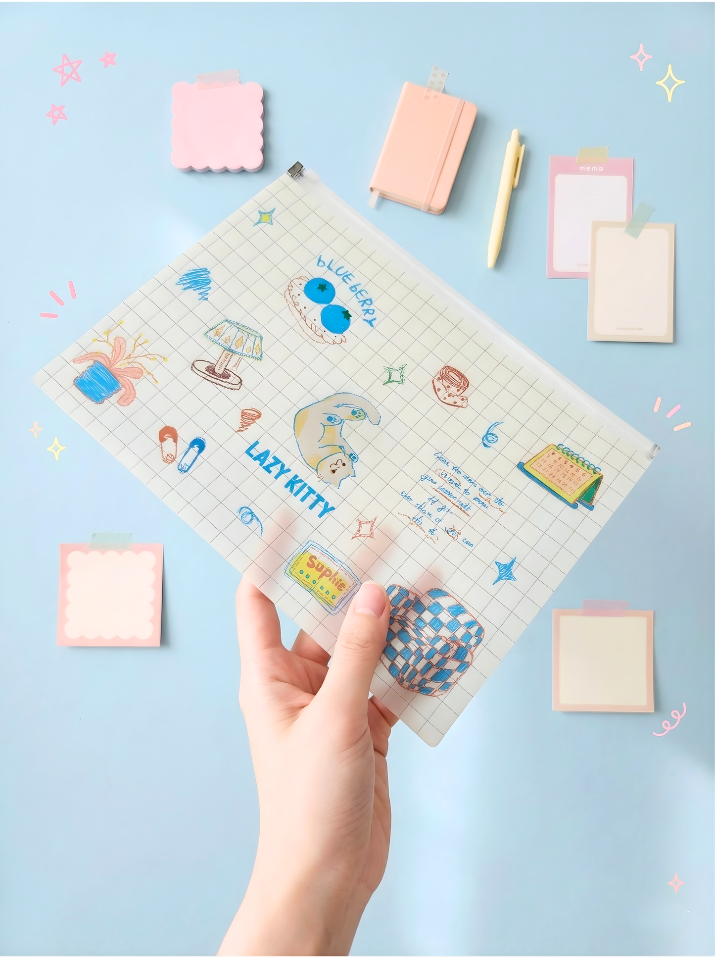 Hand holding a planner with cartoon designs on a light blue background