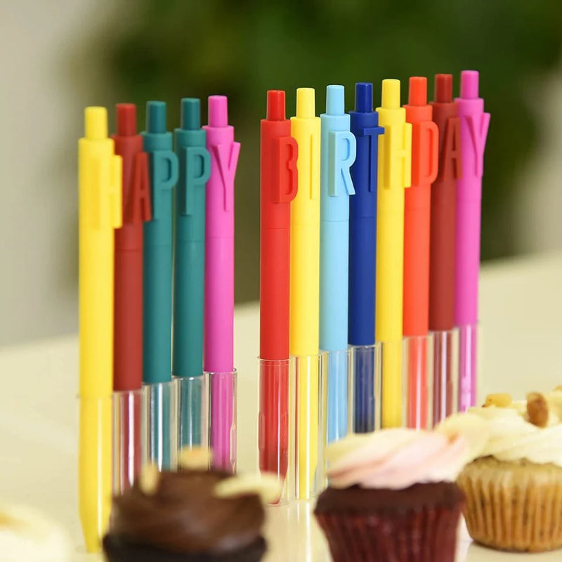 Colorful pens spelling 'Happy Birthday' with cupcakes in the background