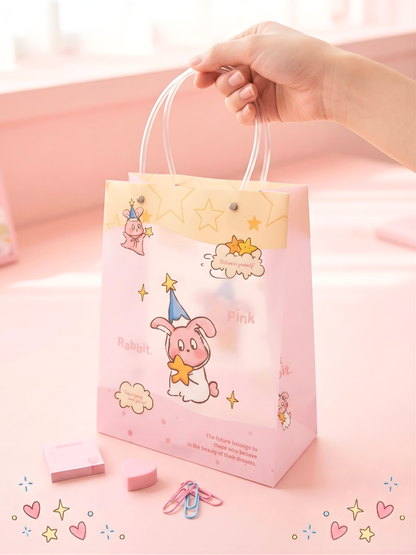 Pink gift bag with cartoon character and text, held by a hand on a light pink background.