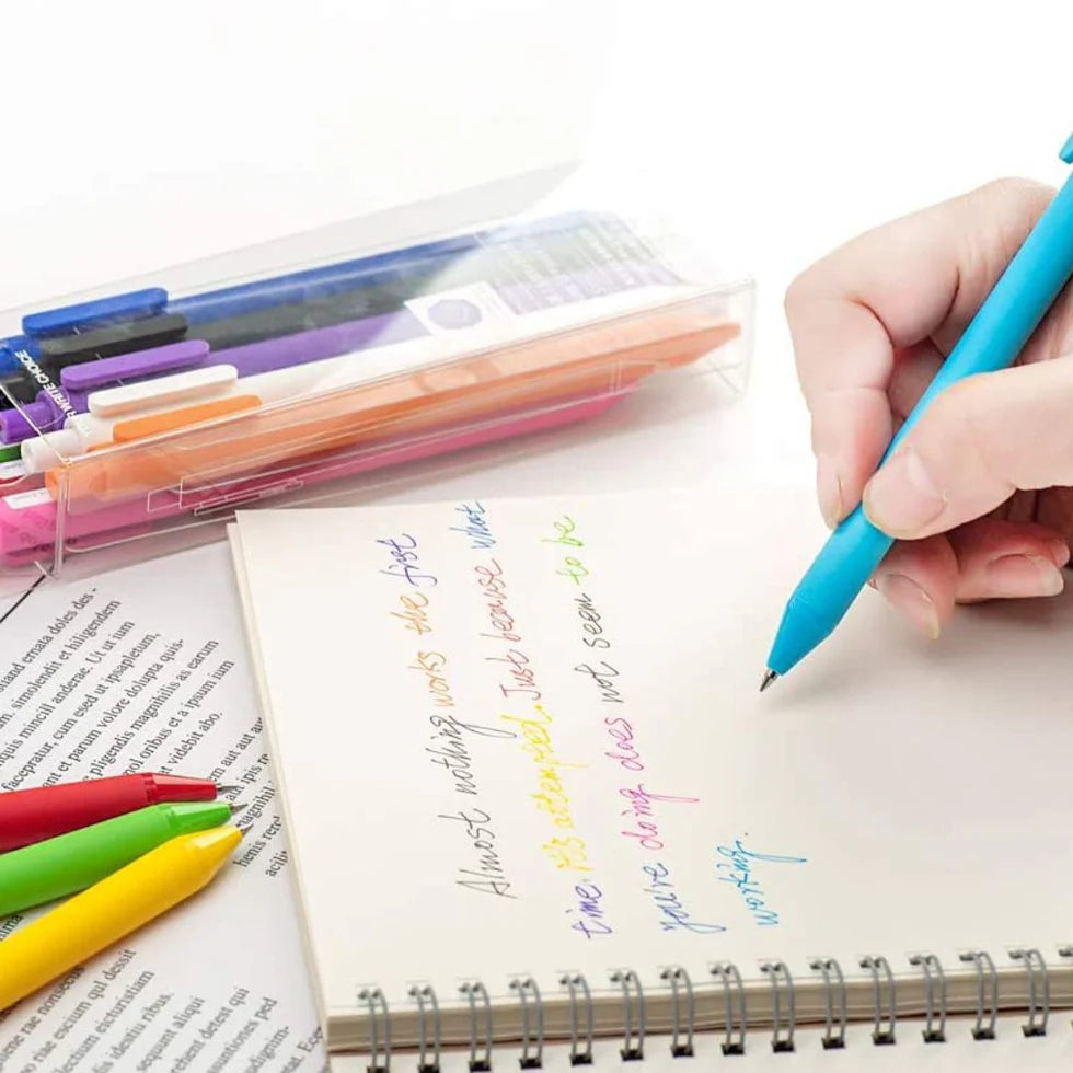 Colorful markers on a notebook with a hand holding a blue marker.